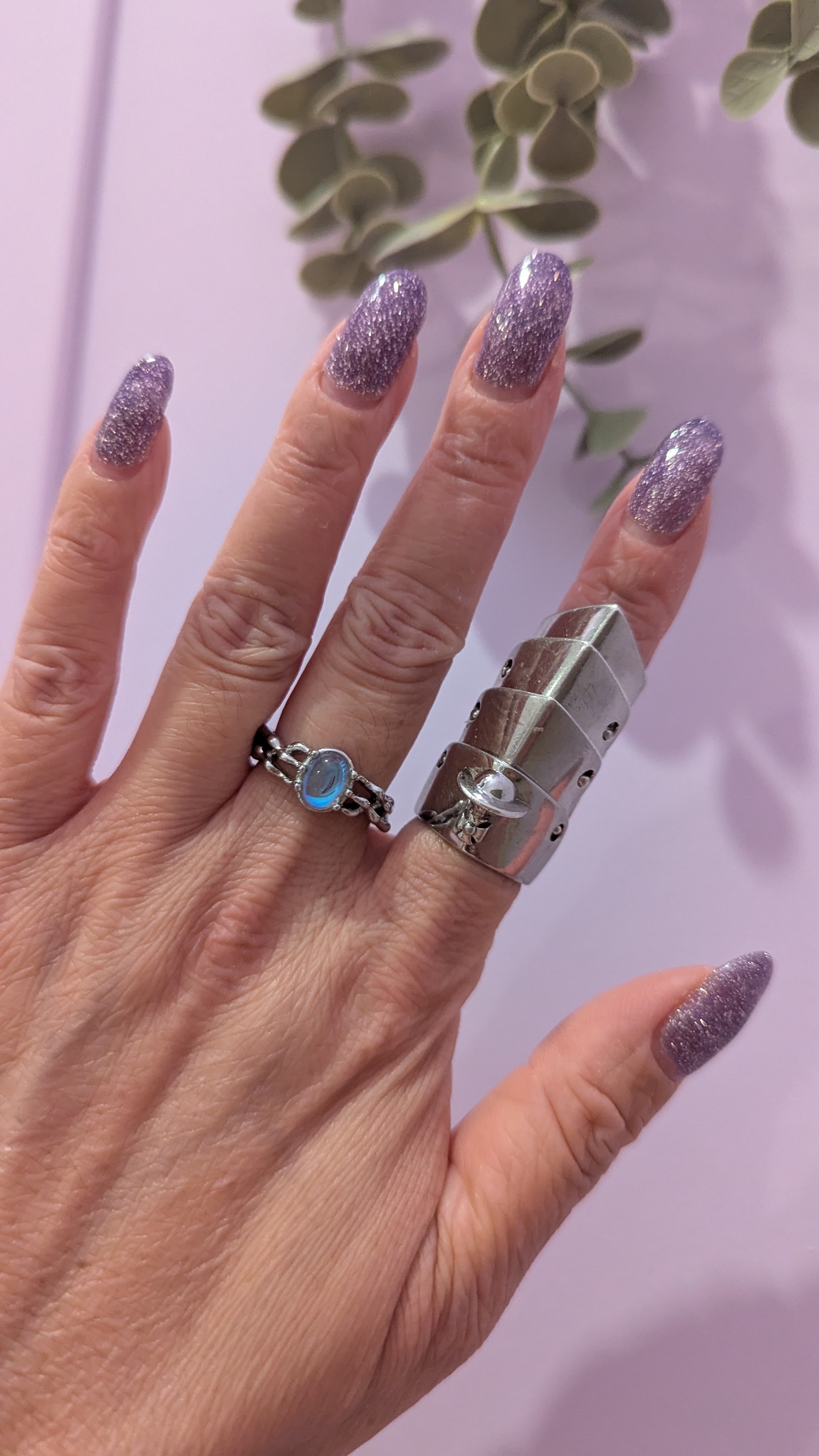 Lila glitternagels met zilveren ringen